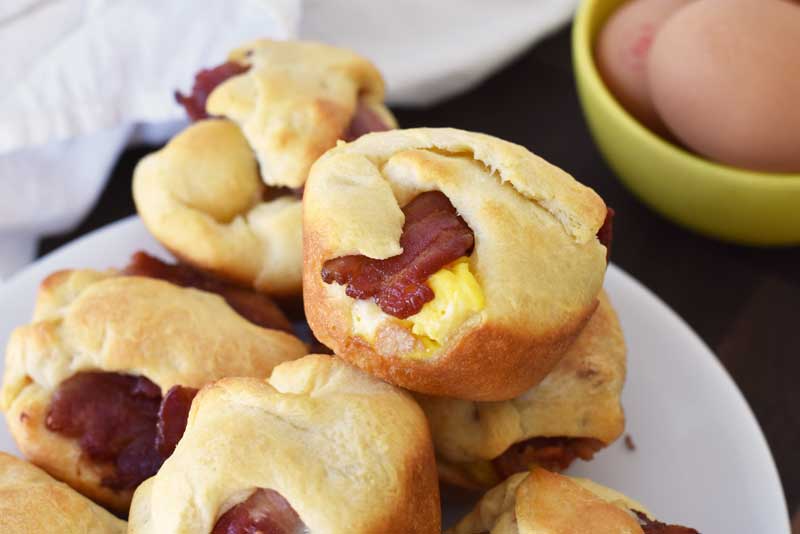 Bacon, Egg, and Cheese in crescent dough. These bites are on a white plate. 