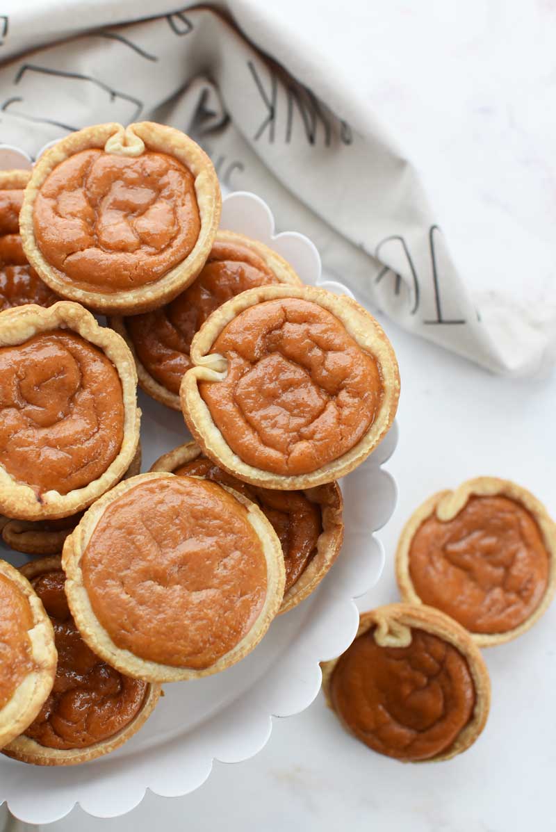 Easy Pumpkin Pies Made in a muffin tin are on a white stand. 