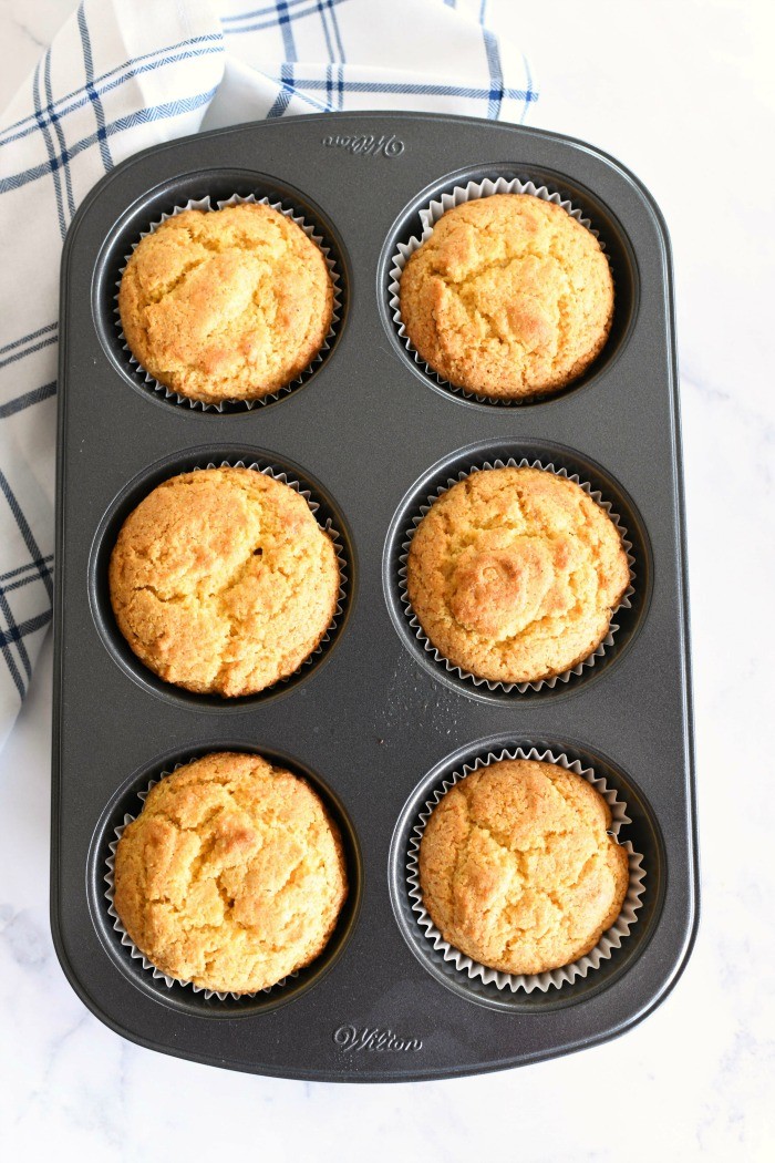 Jumbo Cornbread Muffins baked in a dark metal baking pan. 