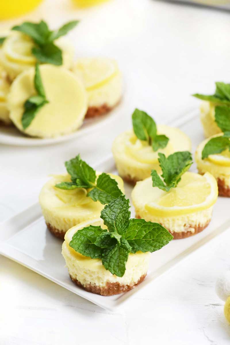 Mini Muffin Tin Cheesecakes with lemon and mint leaves on a white dish.