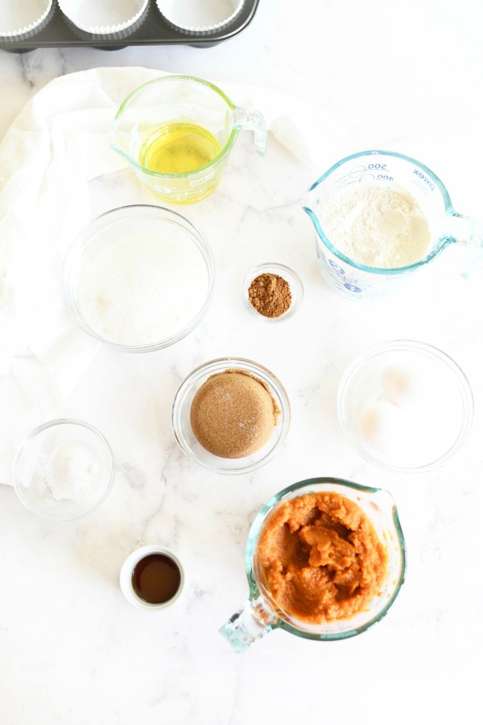 Pumpkin Muffins ingredients in glass bowls on a white table.