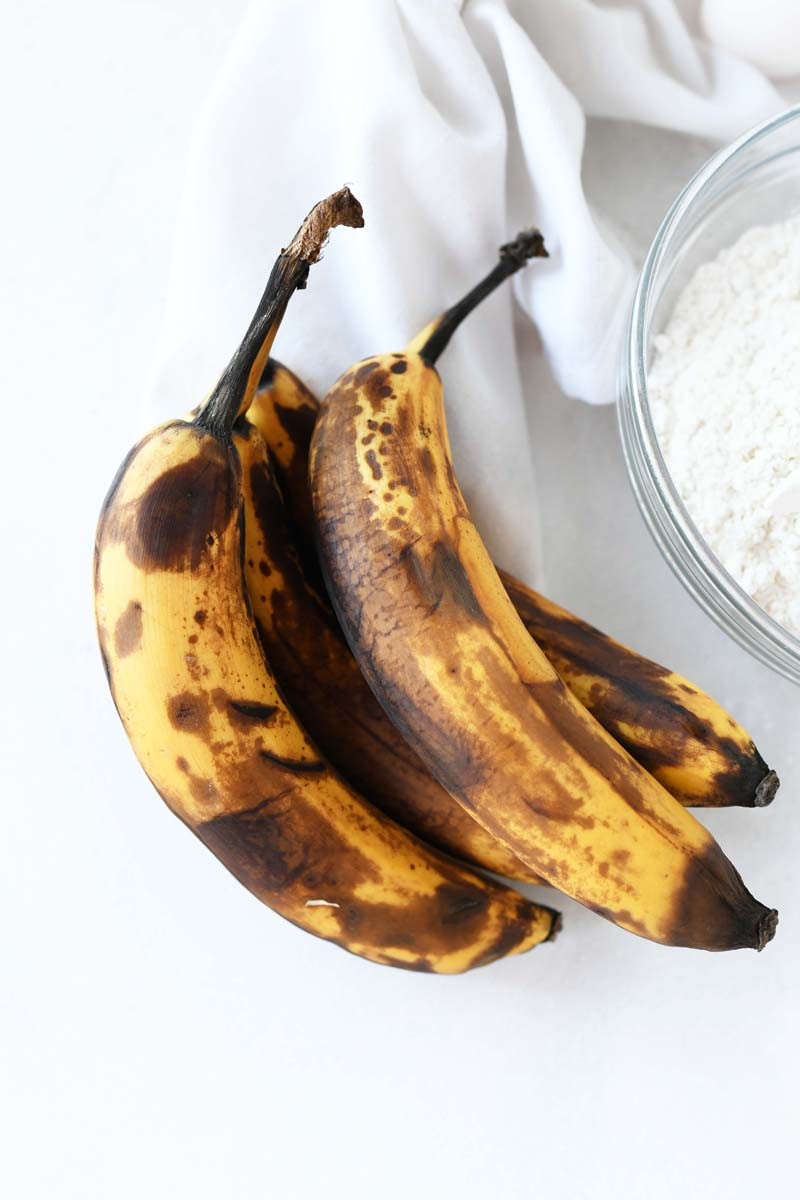 Speckled bananas that are perfect for banana bread muffins. they are on a white table top.