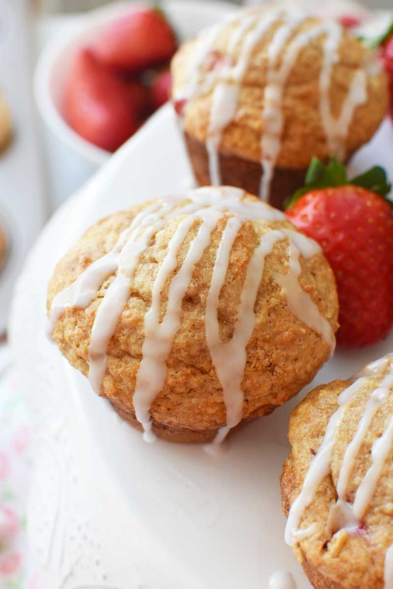 Strawberry Yogurt muffins are iced and on a white cake stand.