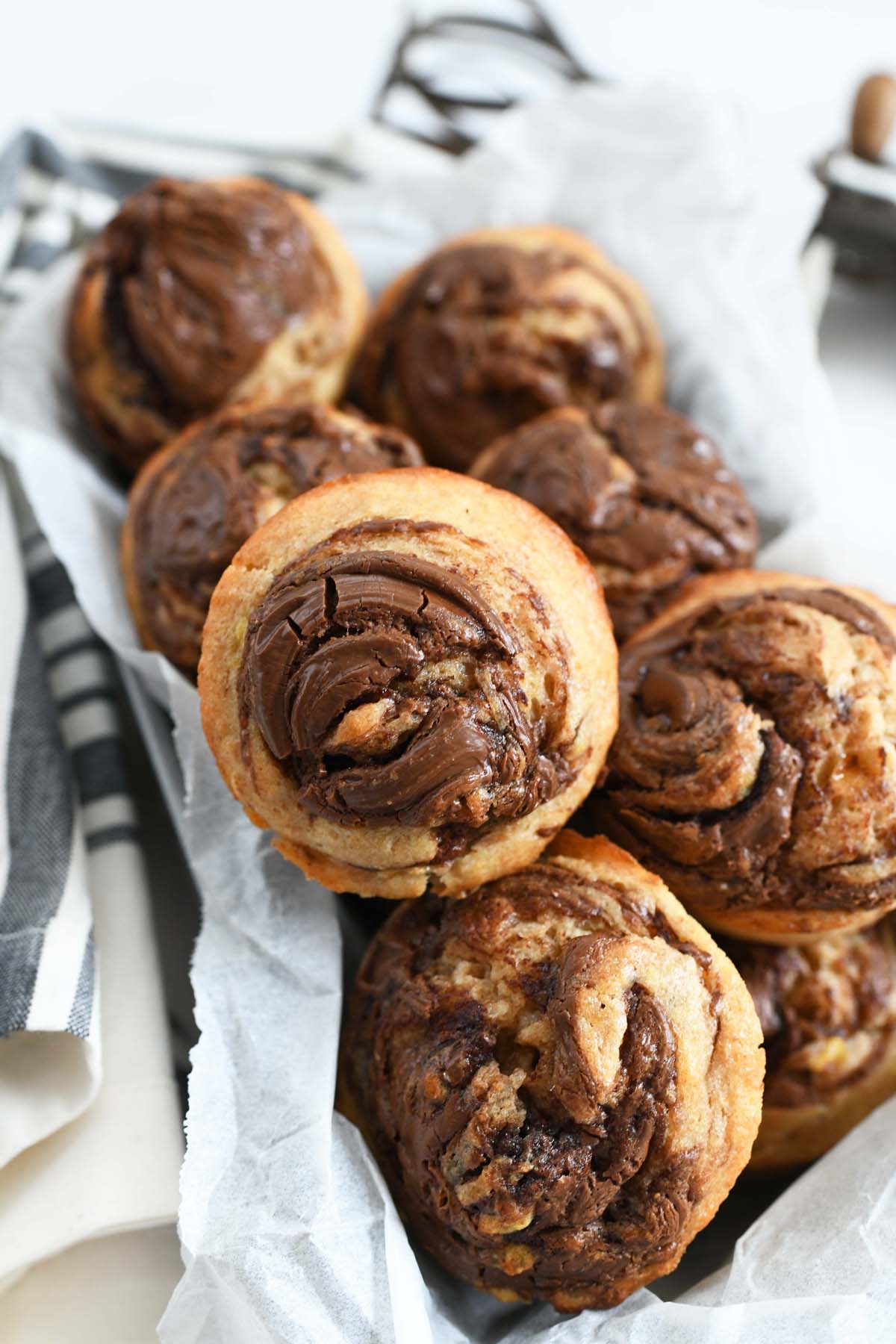 Banana Hazelnut muffins recipe in a parchment lined pan. there is a striped napkin nearby.