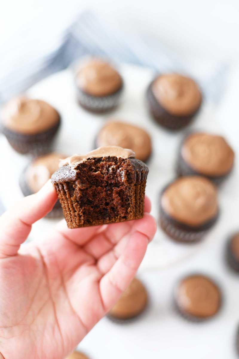 Devil's Food bitten cupcake in a white hand. 