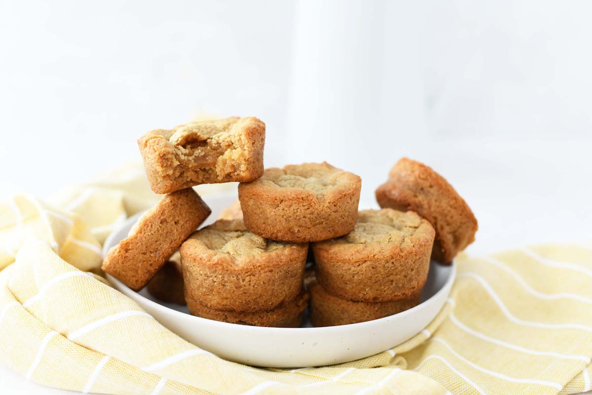 Muffin tin lunchlady brownies on a white plate with a yellow napkin. 