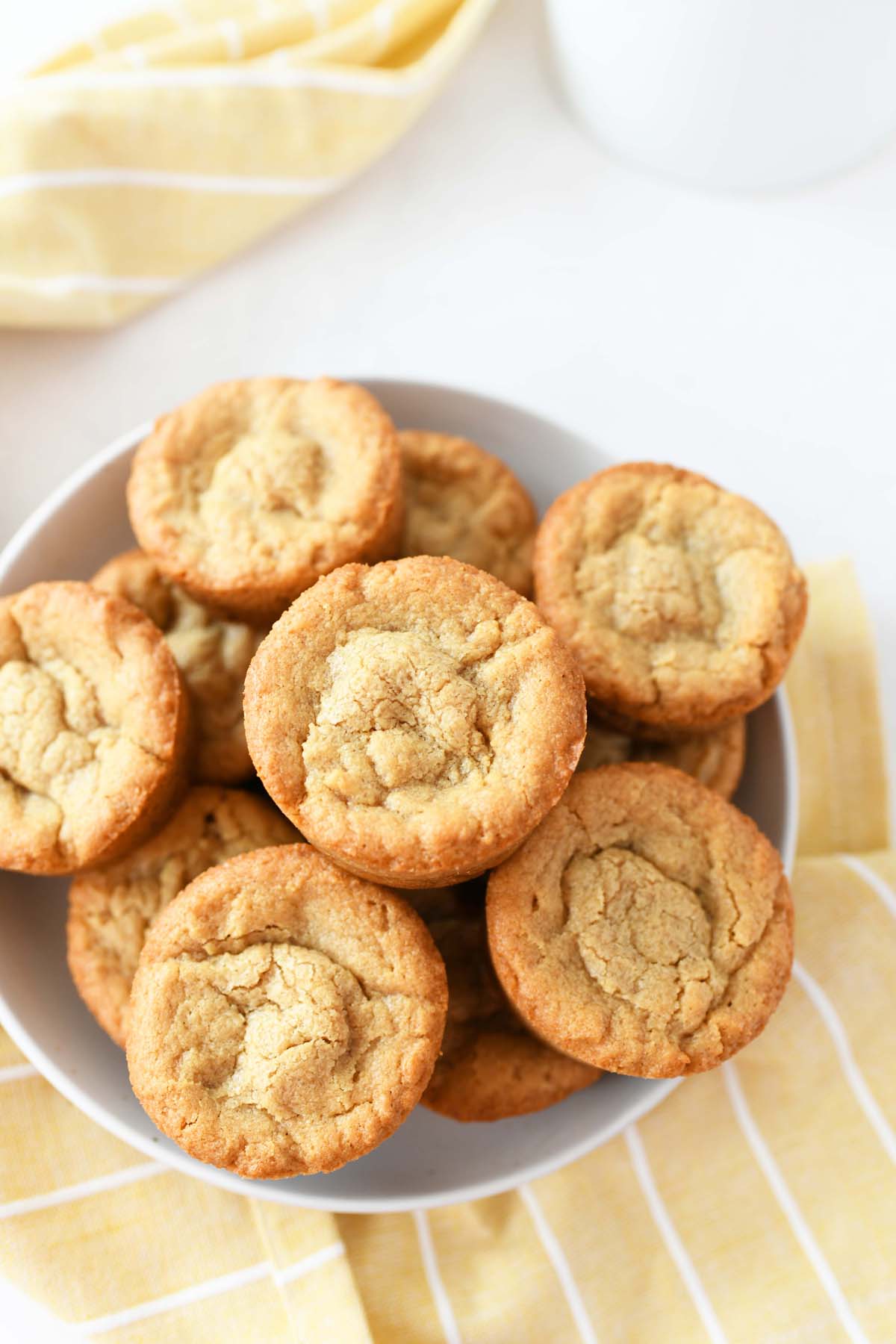 Peanut Butter Muffin Pan brownies in a white bowl. There is a milk container and yellow napkin in the shot.