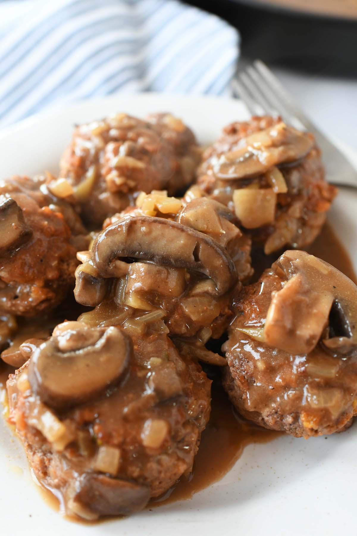 Salisbury Steak in a Muffin Pan Recipe. Mini Salisbury steak patties are served with mushroom gravy on a white plate.