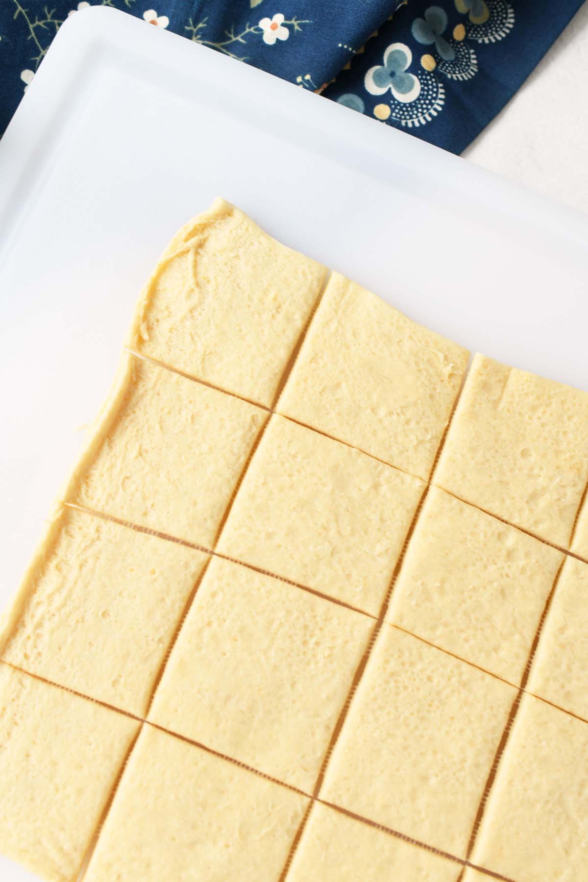 Crescent dough squares on a white cutting board.