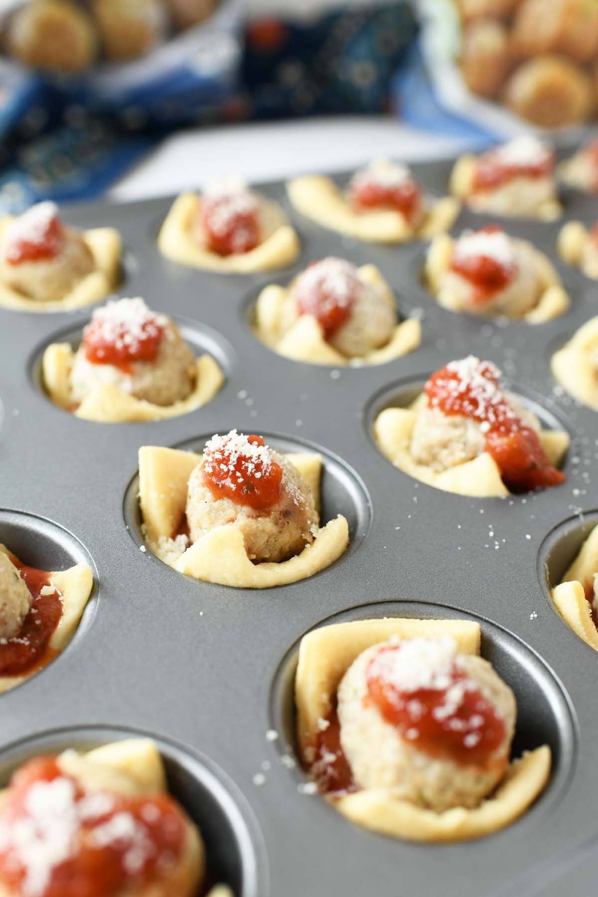 Parmesan on mini meatball cupcakes in a muffin tin.