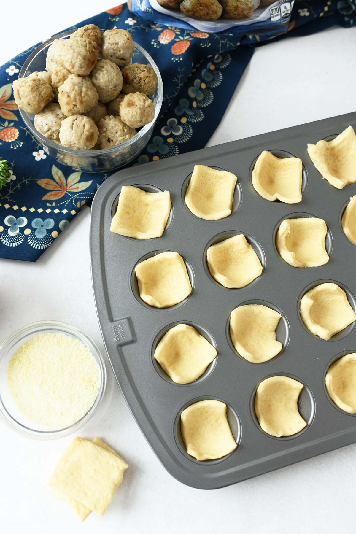 crescent dough in mini silver muffin tin.