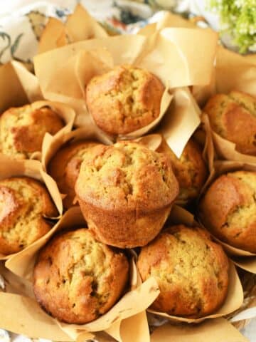 Banana Nut Muffins in a basket with neutral muffin liners.
