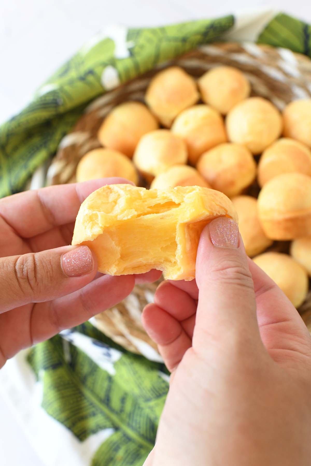 A hand stretching open a golden Brazilian cheesebread.