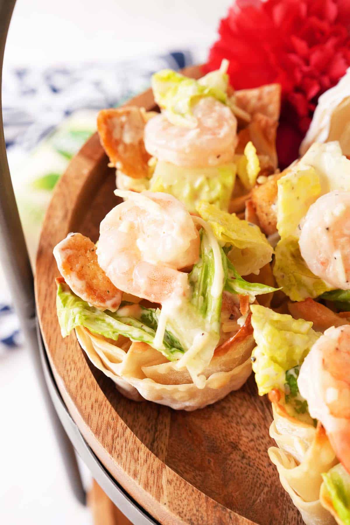 An up-close shot of golden brown caesar wonton cups on a wooden tray.