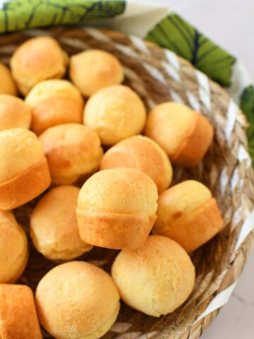 A basket of cheesebread with a green, fern napkin nearby.