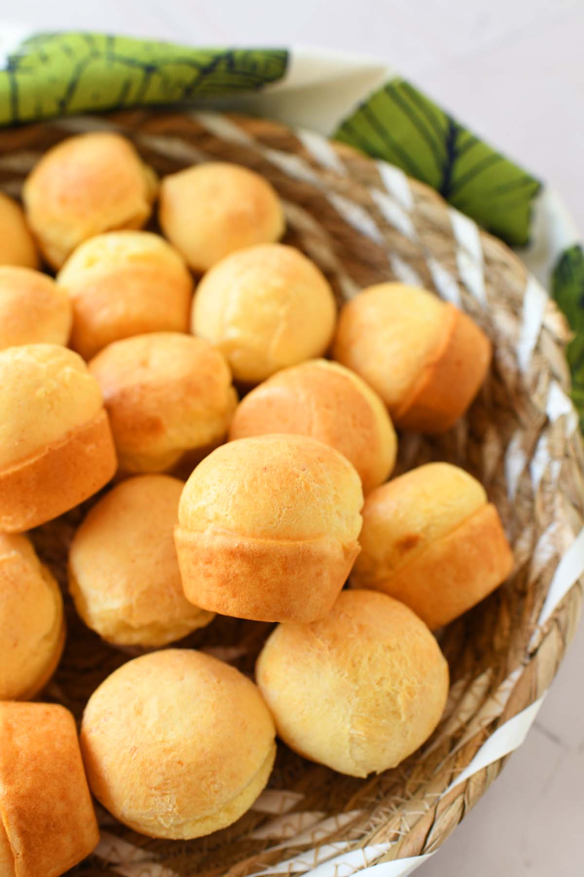 A basket of cheesebread with a green, fern napkin nearby.