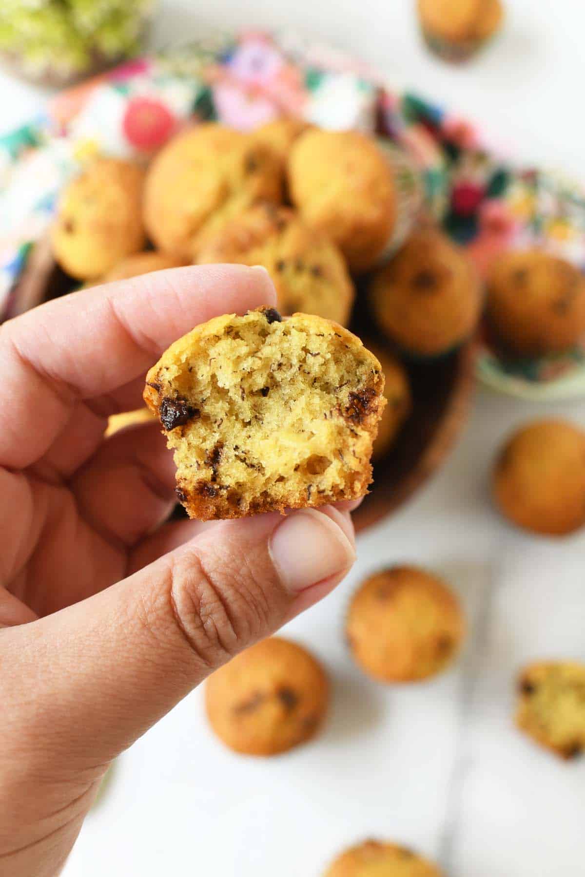 A hand holding a split open mini chocolate chip banana muffin.
