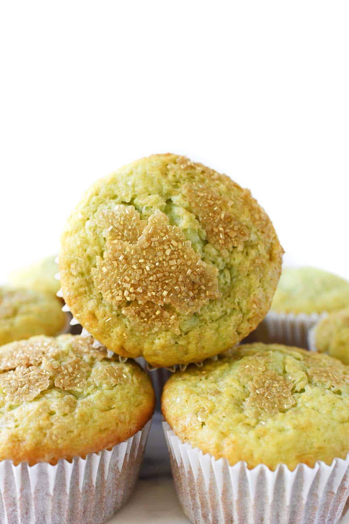 Jumbo Pistachio Pudding Muffins stacked near a white background.