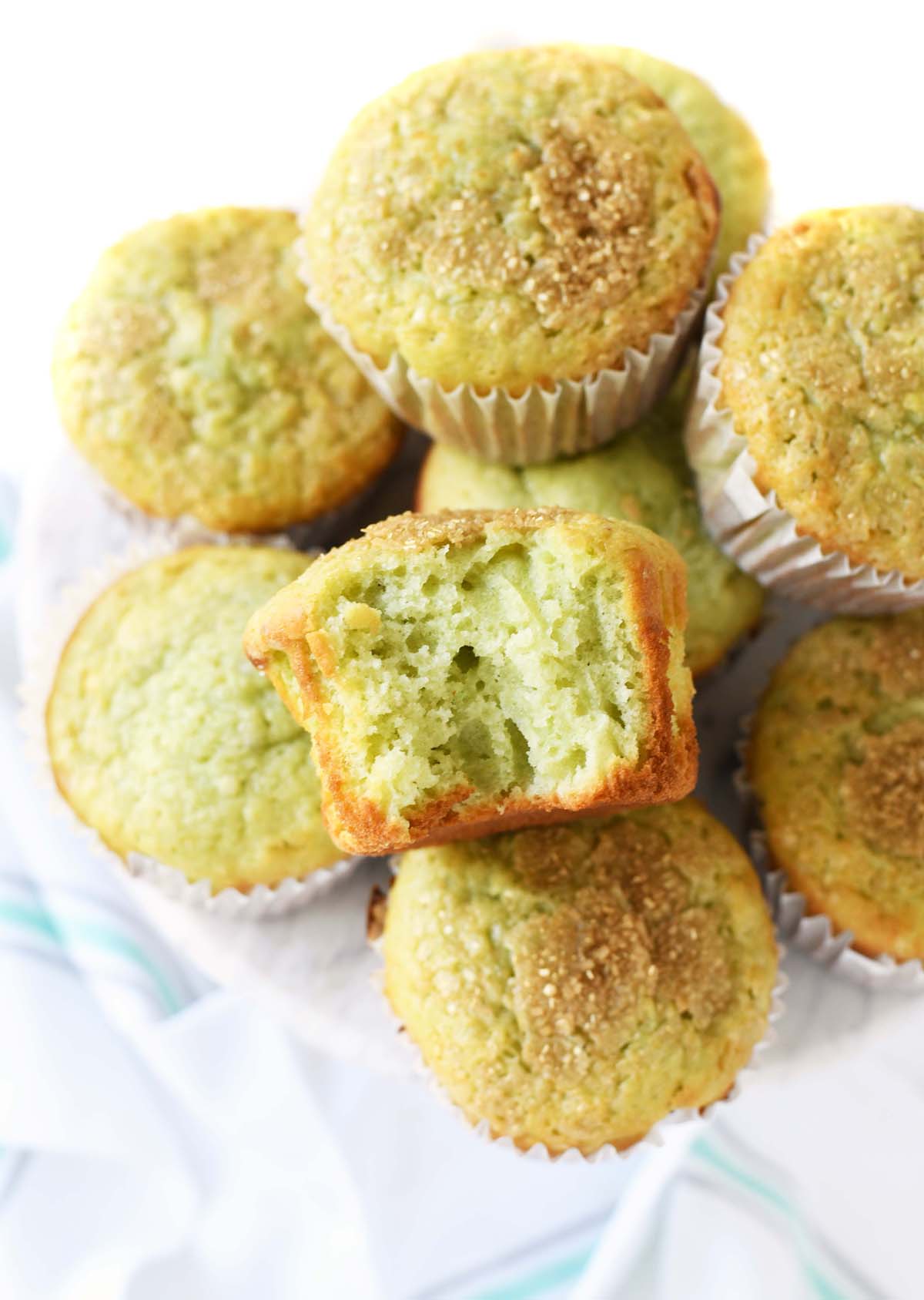 Jumbo Pistachio muffins on a white surface with a bite taken out of one.
