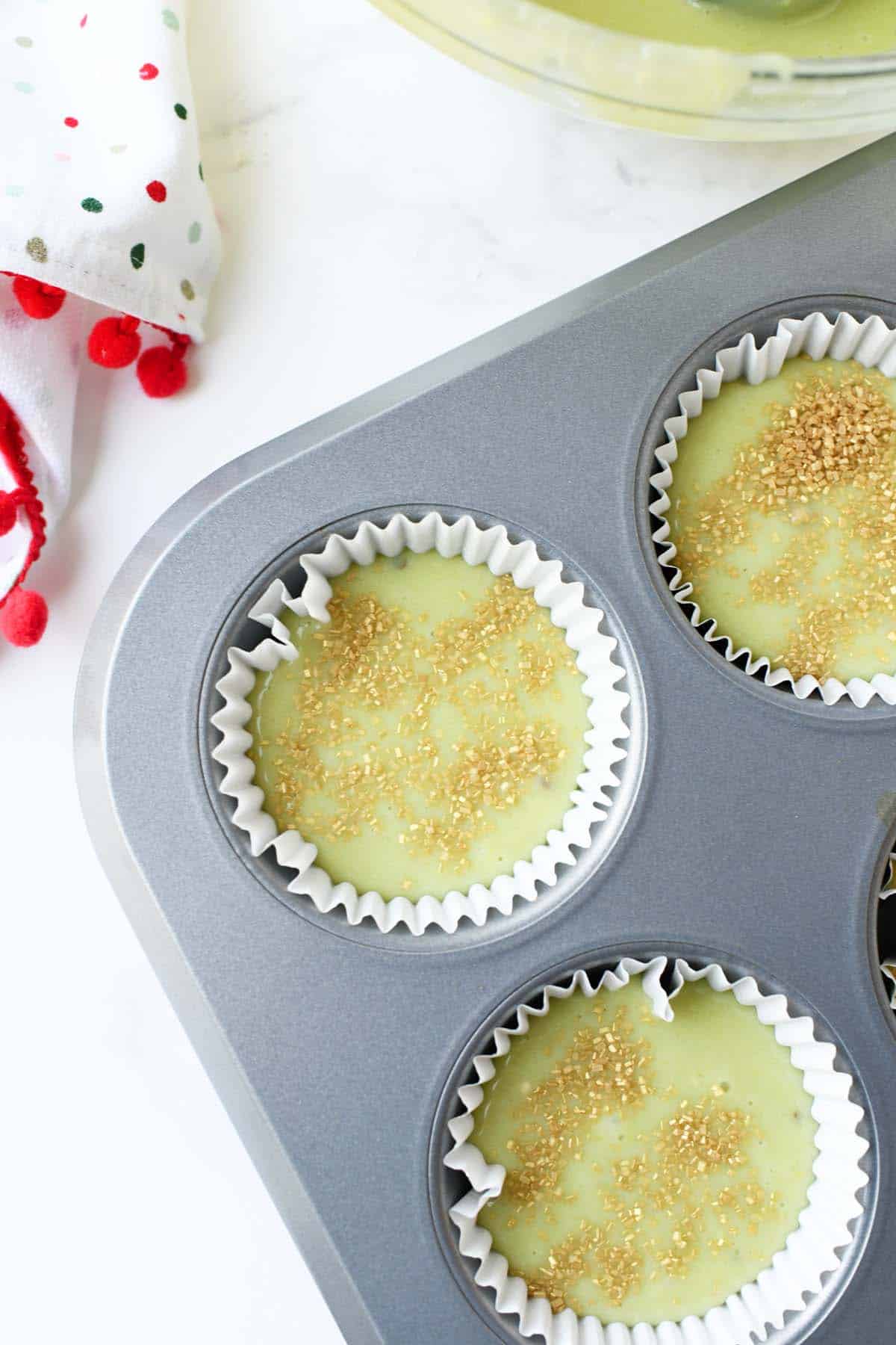 Sanding suagr sprinkled on top of unbaked pistachio pudding muffins.