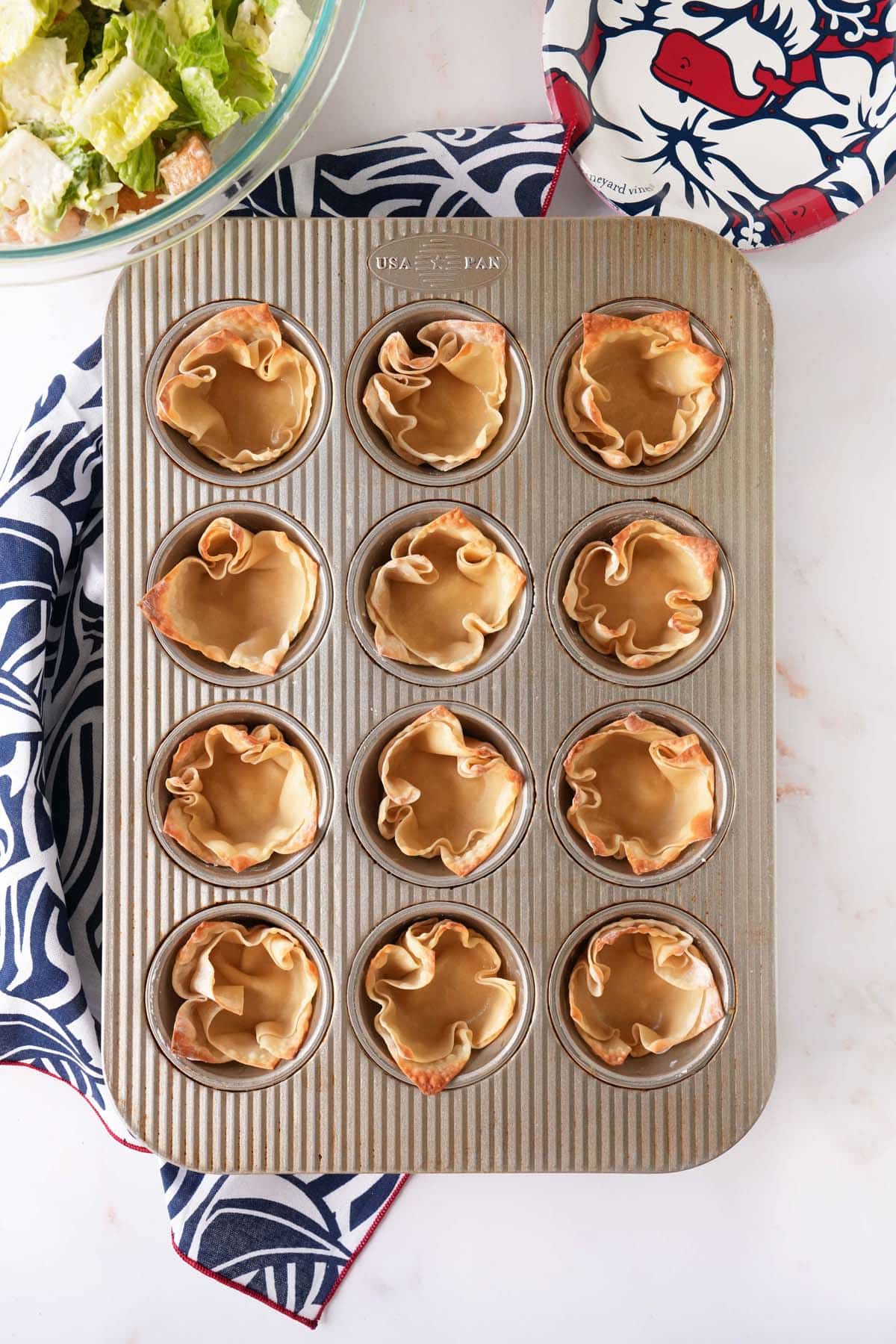 Golden brown wonton cups on a white table near a patriotic napkin.