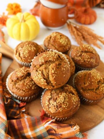 Jumbo pumpkin muffins on a wooden tray with a fall napkin and fall decor.
